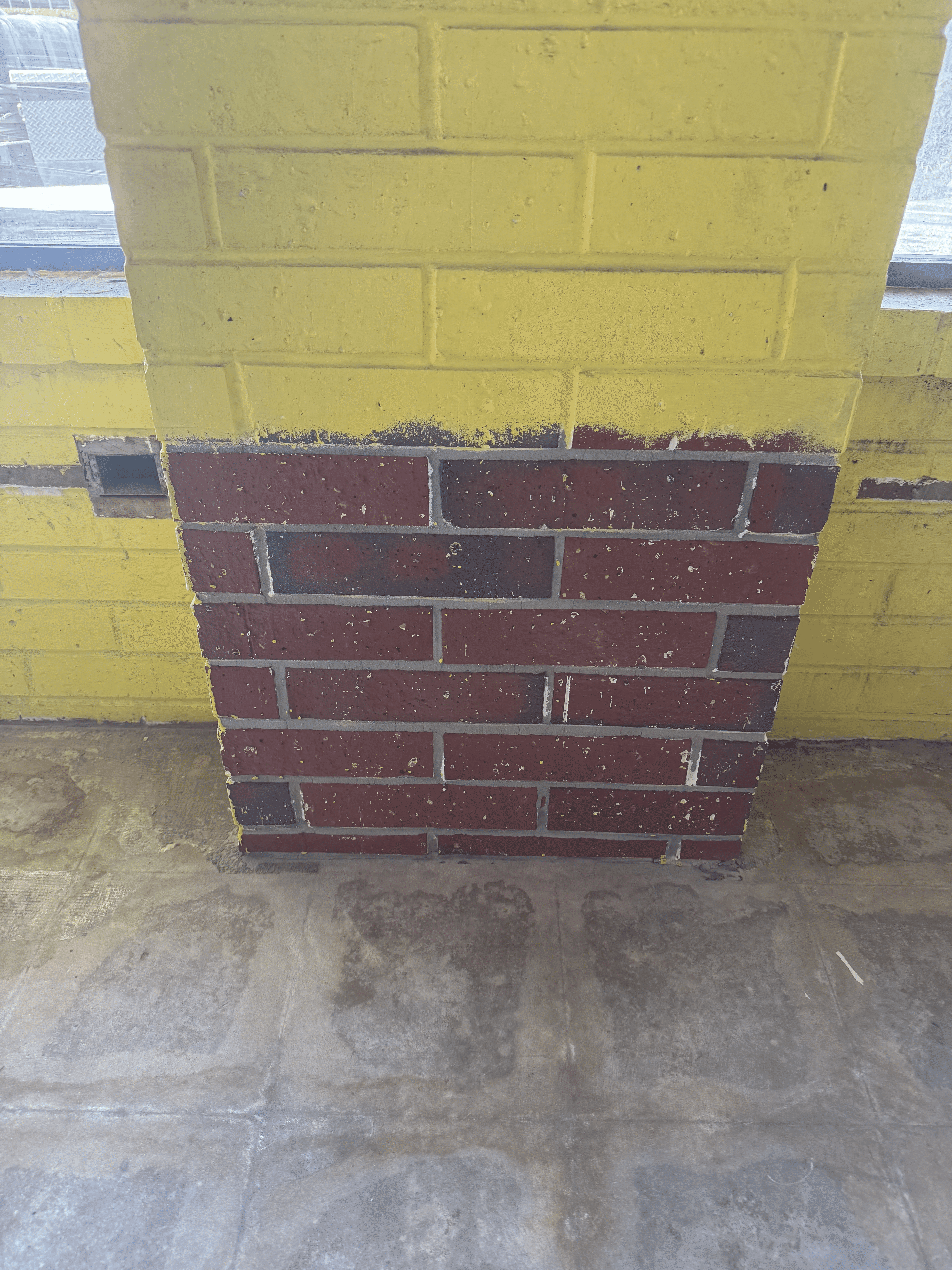 Painted interior brick wall section before paint removal